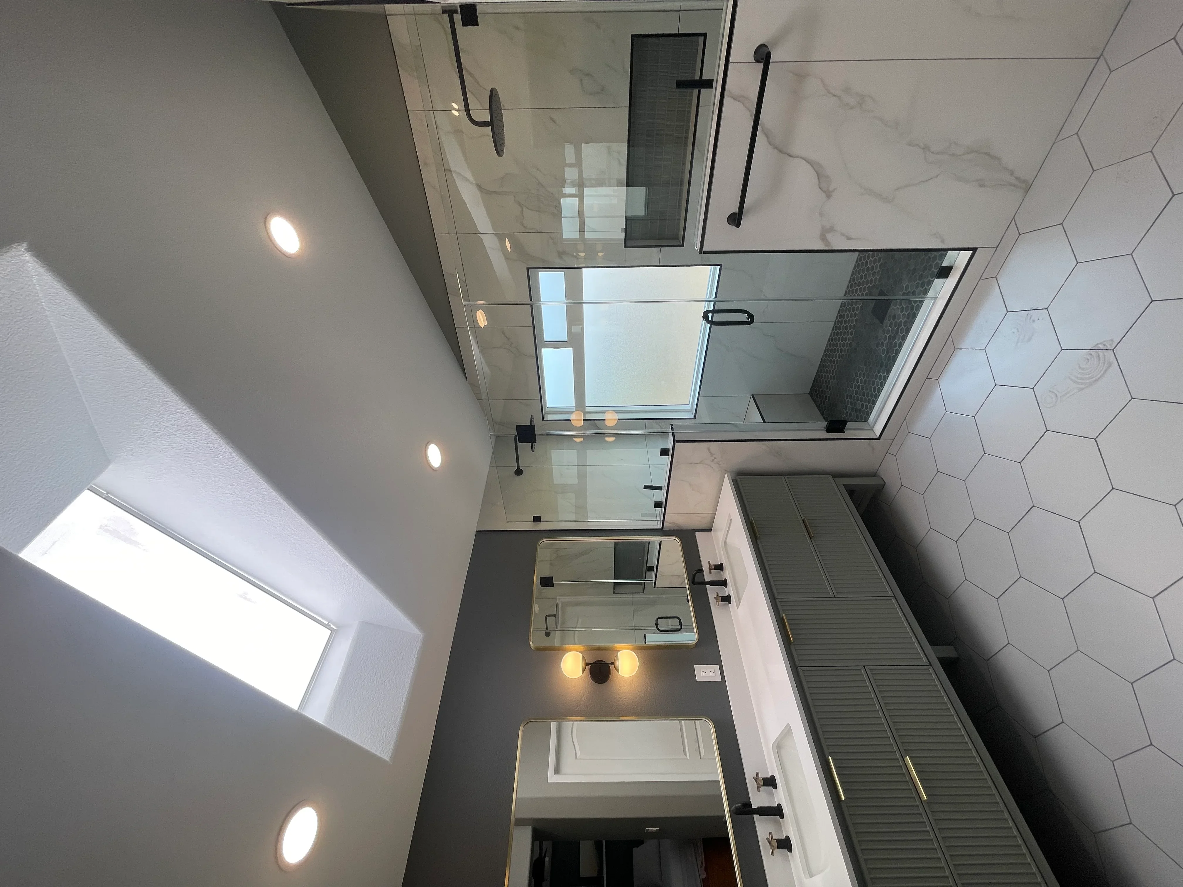 Bathroom with marble tile shower, hexagonal floor tile, frameless glass enclosure, and recessed lighting