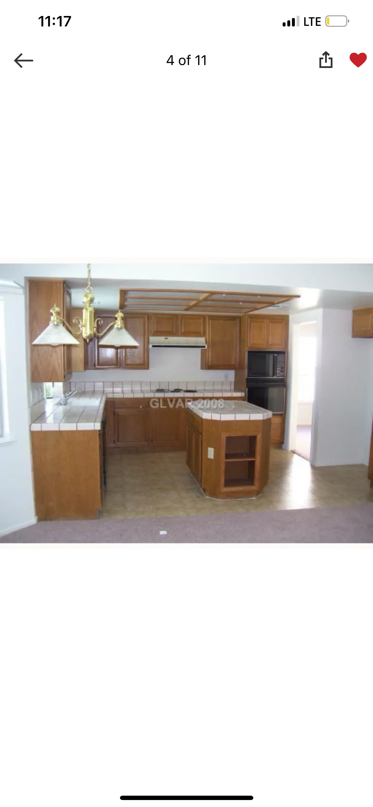 Wood kitchen cabinets with island, subway tile backsplash, and brass pendant lights