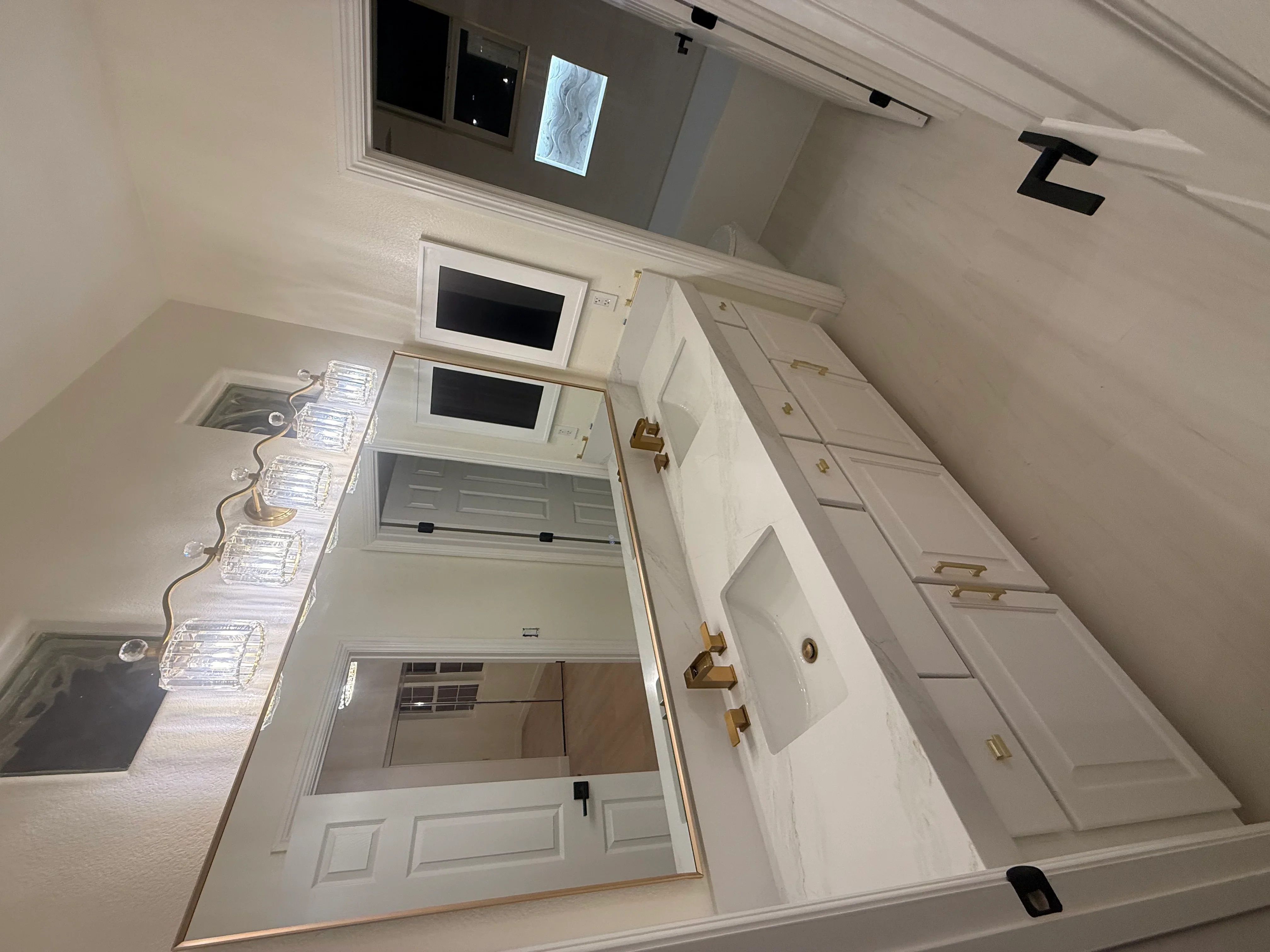 White kitchen cabinetry with brass handles, recessed lighting, and updated electrical outlets during renovation